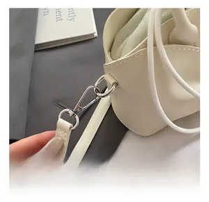 Close-up of premium silver metal spring hook and beige leather strap on fashion handbag