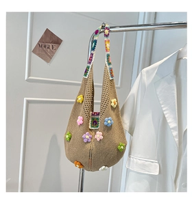 Detail of handmade knit tote bag featuring colorful 3D floral embroidery and woven strap