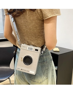 Detail of vintage camera shaped crossbody bag featuring textured leather and print