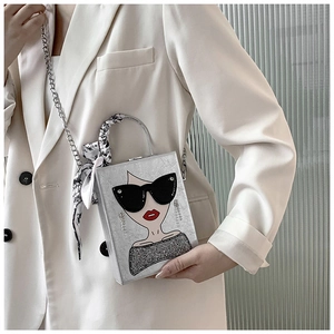Detail of silver box bag with lady illustration, chain strap and silk scarf handle decor