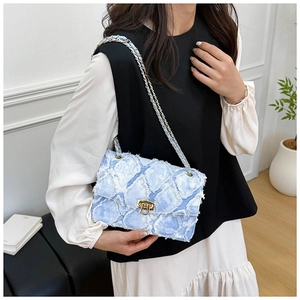 Détail du sac à chaîne en denim bleu clair matelassé avec bords effilochés et fermoir doré