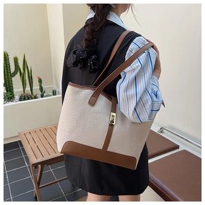 Detail of the chic beige woven tote bag with brown leather trim and golden metal lock