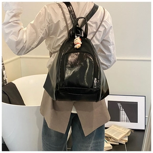 Close-up of black glossy backpack with cute rabbit charm showing texture and details