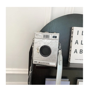 Close-up of silver camera-shaped crossbody bag featuring metallic pleated PU and lens detail