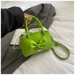 Detail of green bow handbag with silver heart charm and white drawstring liner