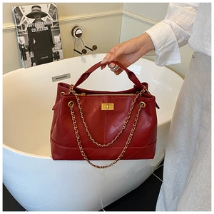 Detailed macro of burgundy quilted leather texture with gold-tone twist lock and chain