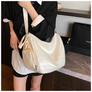 Detail of creamy white hobo bag with mini coin purse and leather texture on model