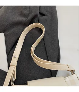 Close-up of cream shoulder bag featuring adjustable strap details and metal hardware