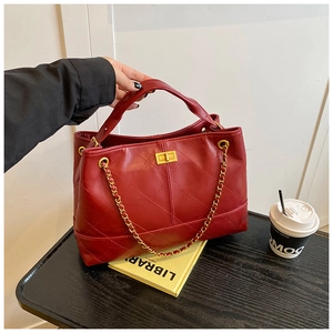 Detailed view of red quilted leather tote bag featuring gold clasp and chain strap