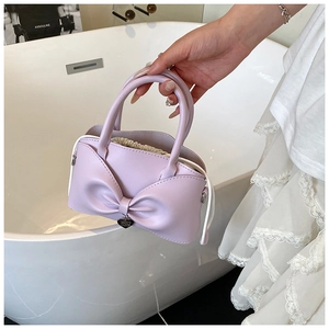 Detail of lavender handbag featuring a large bow and drawstring lining by a bathtub