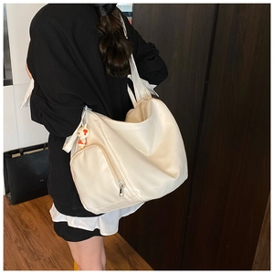 Detail view of cream white PU leather tote bag with a cute doll charm and outer pocket