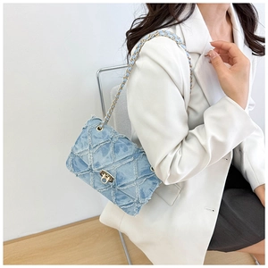 Détail du sac bandoulière en denim bleu clair avec motif losanges et bords effilochés