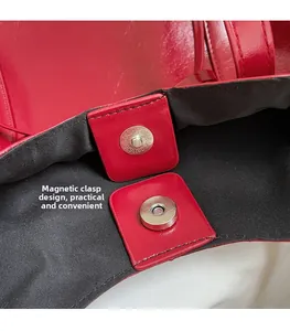 Détail du sac à main en cuir rouge montrant le fermoir magnétique et la doublure noire