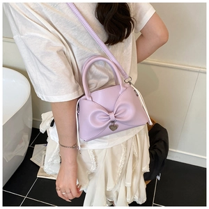 Detail of lavender purple bow handbag with heart pendant and adjustable shoulder strap