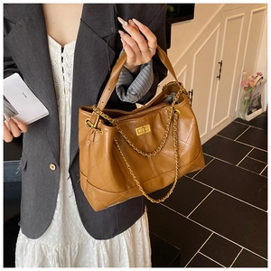 Detail of dark brown quilted leather tote bag with gold chain strap and secure metal lock