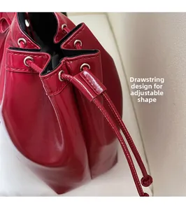 Détail du sac seau en cuir rouge avec œillets argentés et cordon de serrage réglable