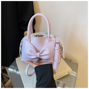Detailed view of lavender handbag featuring large bow, heart charm and drawstring liner