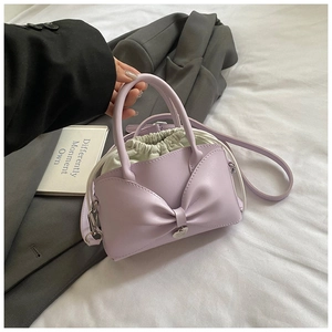 Lavender bow handbag featuring a drawstring inner bag and silver hardware on white linen