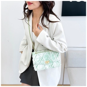 Détail du sac bandoulière en tweed vert clair avec bords effilochés et chaîne dorée