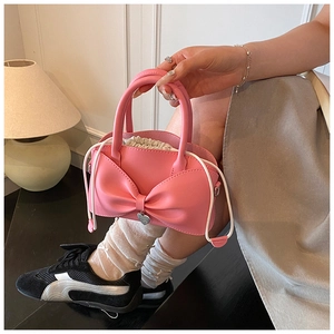 Detail of pink bow handbag with cream drawstring pouch and heart charm