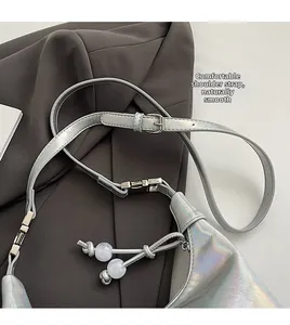 Détail de la bandoulière réglable avec boucle en métal et glands perlés sur le sac argenté