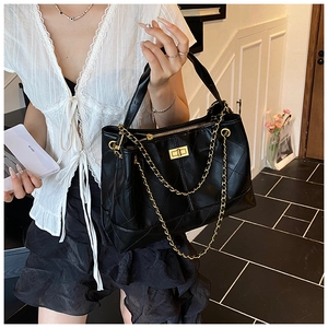 Detail of black quilted leather tote bag with gold chain strap and turn-lock closure
