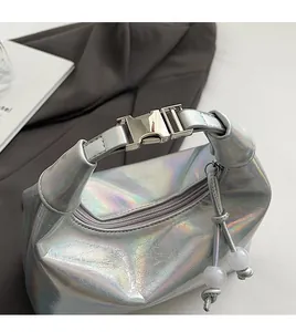 Gros plan sur un sac argenté métallisé avec boucle de poignée et détail de pompon perlé