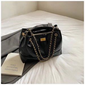 Detail of black quilted leather texture and gold chain strap on the tote bag