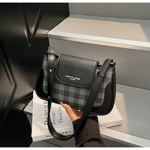 Detailed view of the checkered underarm bag on a prop book with minimalist leather flap