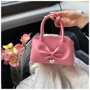 Detailed view of pink bow handbag featuring white drawstring pouch and heart charm pendant