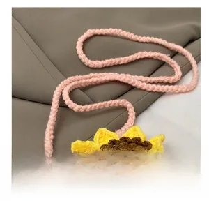 Gros plan sur la bandoulière en tricot rose fixée au sac au crochet tournesol