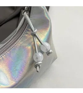Vue macro du cuir holographique argenté avec fermeture éclair et gland à perles