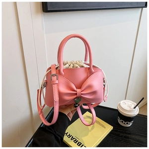Detailed view of pink bow handbag with heart charm and white drawstring liner