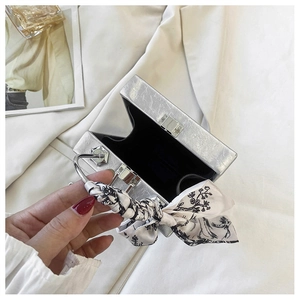 Detailed view of silver metallic box bag featuring pleated texture and silk scarf handle
