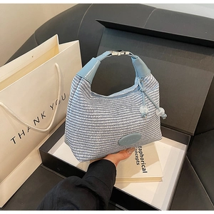Detailed macro view of woven hobo bag with light blue leather handle and metal buckle