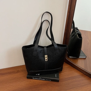 Large black woven tote bag with gold metal lock and leather straps for commute