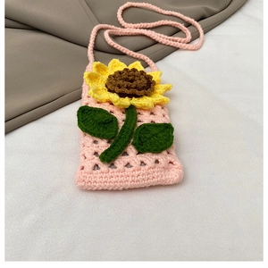 Détail d'un sac bandoulière en tricot rose orné d'un grand motif de tournesol jaune