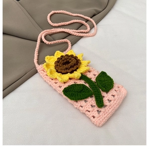 Détail d'un mini sac en tricot rose fait main avec motif de tournesol crocheté jaune
