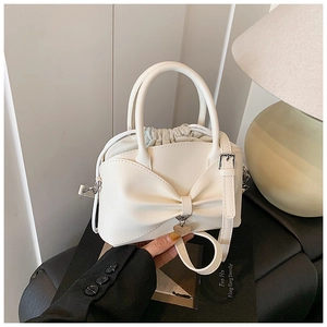 Detail of off-white bow handbag featuring heart pendant and drawstring closure