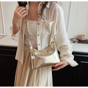 Gros plan d'un sac demi-lune doré métallisé avec texture plissée et charms en perles