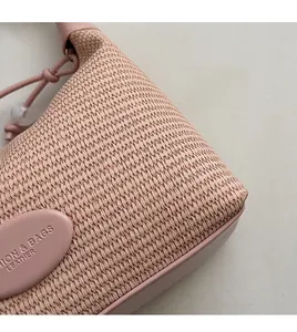 Detailed view of pink woven handbag featuring premium leather trim and texture details