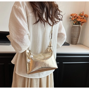 Détail du sac doré métallisé avec texture plissée et charm perle porté à l'épaule