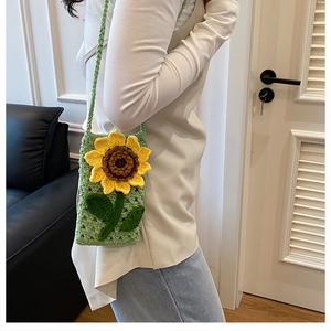 Détail d'un sac bandoulière vert tricoté main avec motif de tournesol jaune en relief
