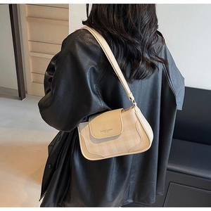 Detail of checkered pattern and brand text on stylish cream faux leather underarm bag