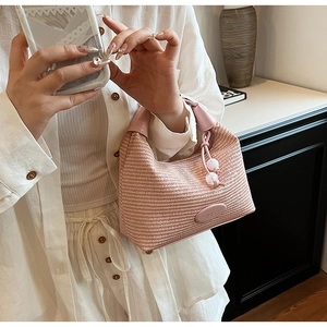 Pink woven handbag with leather handle and decorative white beads on the zipper