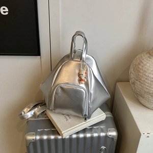 Silver geometric backpack with metallic finish and cute rabbit charm on a suitcase