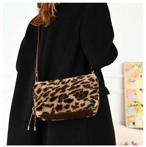 Detailed close-up of leopard faux fur crossbody bag with brown leather strap and tassels
