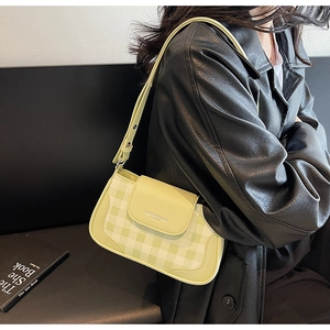 Detail of green plaid baguette bag with adjustable strap and leather flap closure