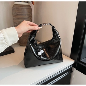 Détail du sac demi-lune noir brillant avec boucle argentée et breloques en perles