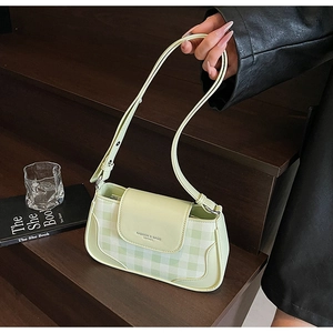Detail of light green plaid shoulder bag with fashion leather embossing on wood stairs